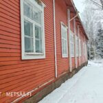 Entisen punaisen koulun pitkä julkisivu ja useita ikkunoita talvipäivänä.