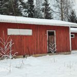 Punainen puurakenteinen varastorakennus Kovelahden koulun pihapiirissä.