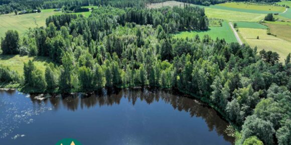 Dronekuva Saarilahden metsäisestä rantapalstasta ja sitä ympäröivistä pelloista Ikaalisissa
