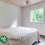 Valoisa makuuhuone metsämaisemaan avautuvalla ikkunalla